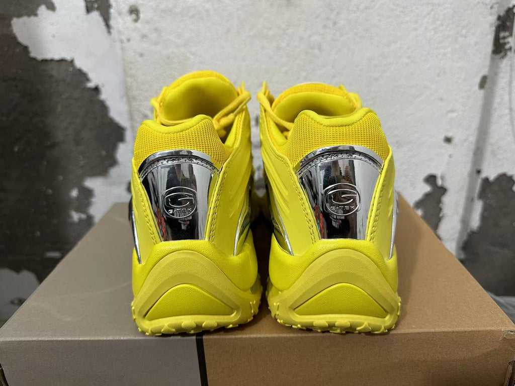 Rear view of yellow sneakers with reflective silver-tone heel details.