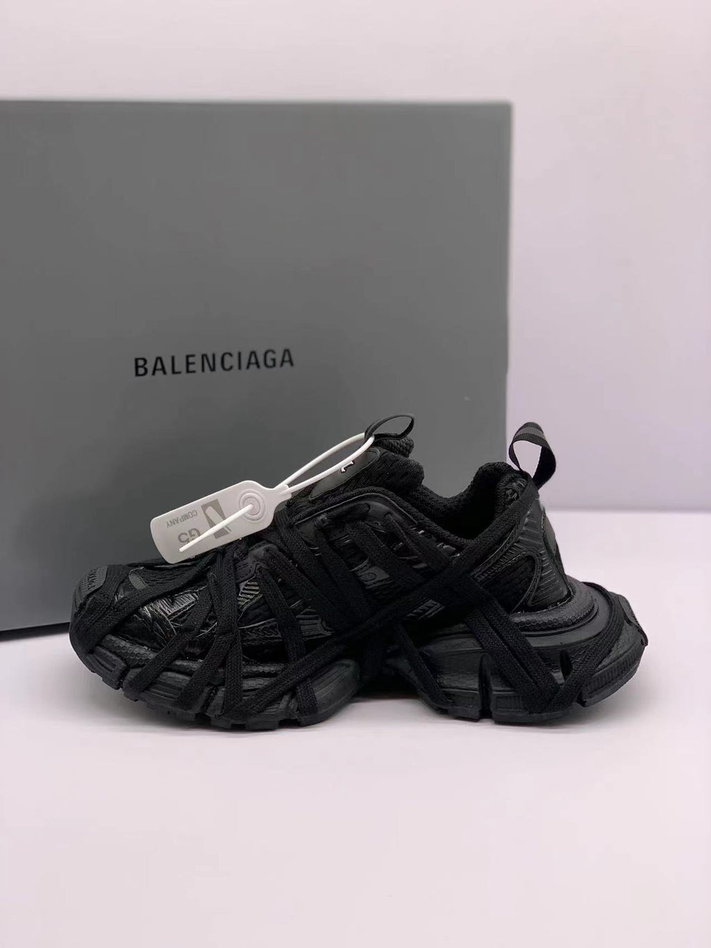 Black sneakers shown from the opposite side, highlighting the layered lace construction and textured panels.
