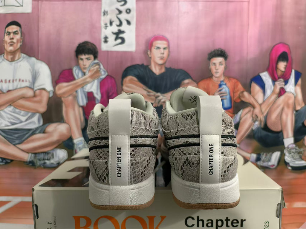 Rear view of gray patterned Nike Book 1 sneakers with white heel tabs and gum-colored outsoles, displayed on a shoe box.