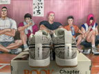 Rear view of gray patterned Nike Book 1 sneakers with white heel tabs and gum-colored outsoles, displayed on a shoe box.