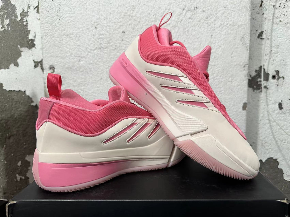 Pair of pink and cream Adidas Dame 9 basketball shoes shown from the side