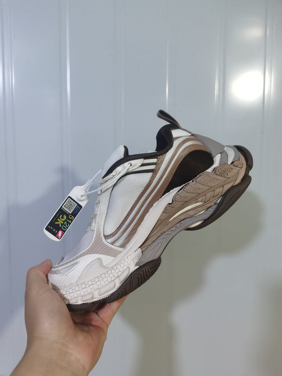 Top and side angled view of the brown, beige, white, and grey Balenciaga Triple S 2 2290 sneaker with a hanging product tag.