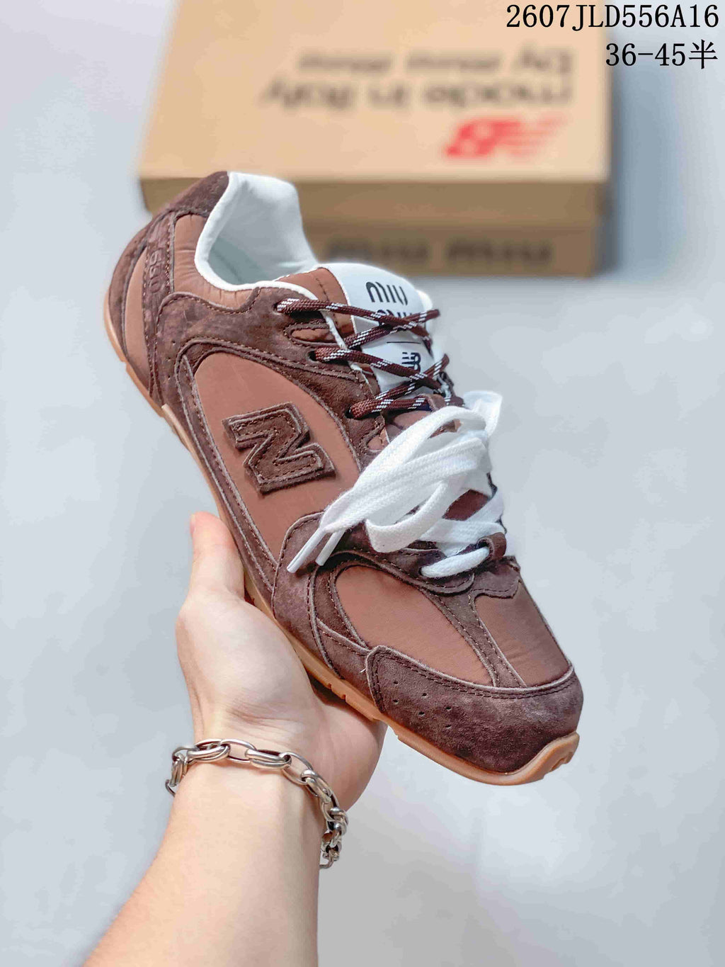 Close-up side view of the brown sneaker showing layered panels, New Balance branding, white laces, and a gum-colored outsole.