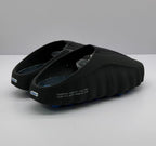 Rear three-quarter view showing the open heel, blue outsole pods and printed side text.