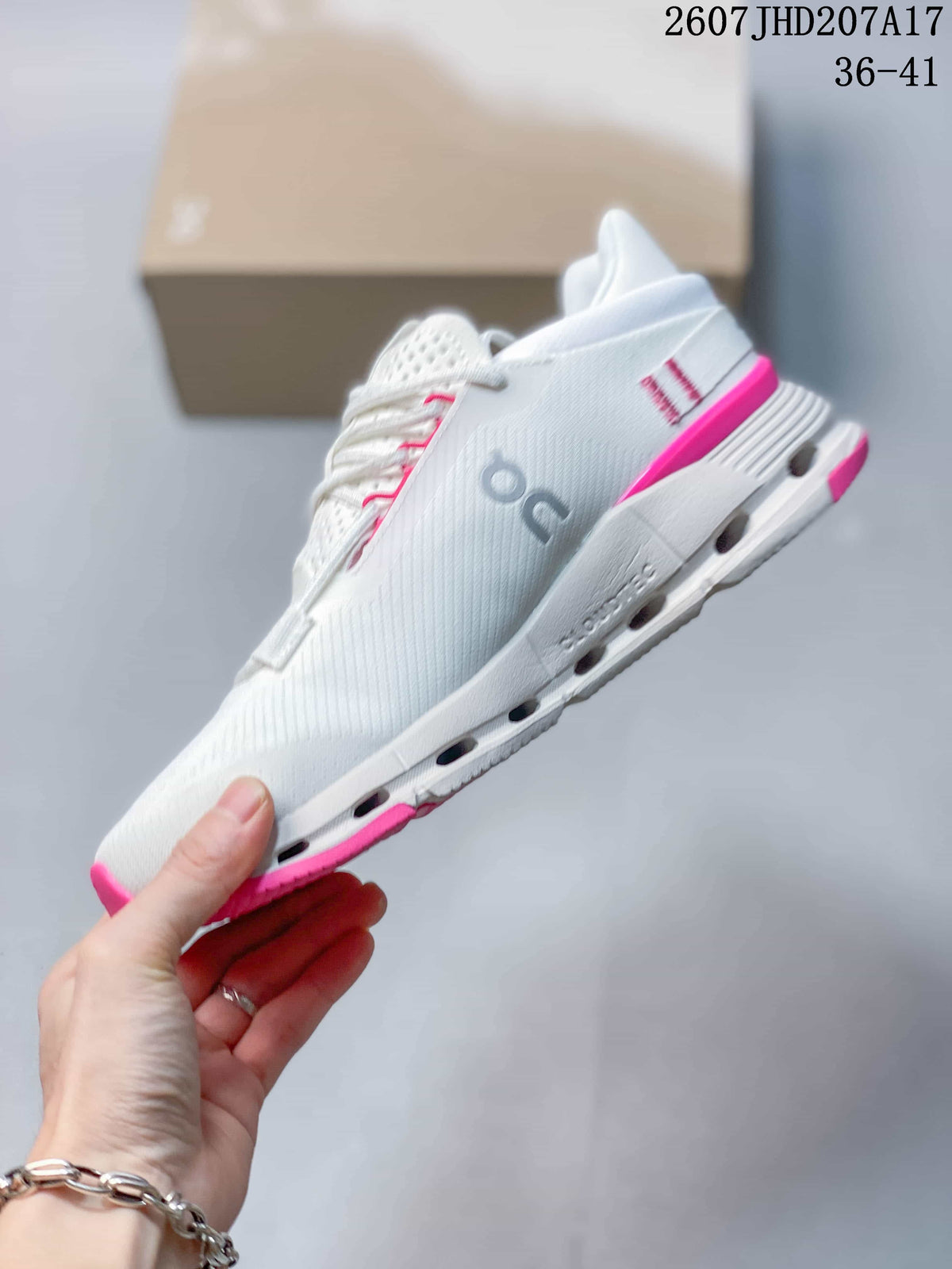 Side view showing the white upper, gray On branding, pink heel detail, and segmented midsole.