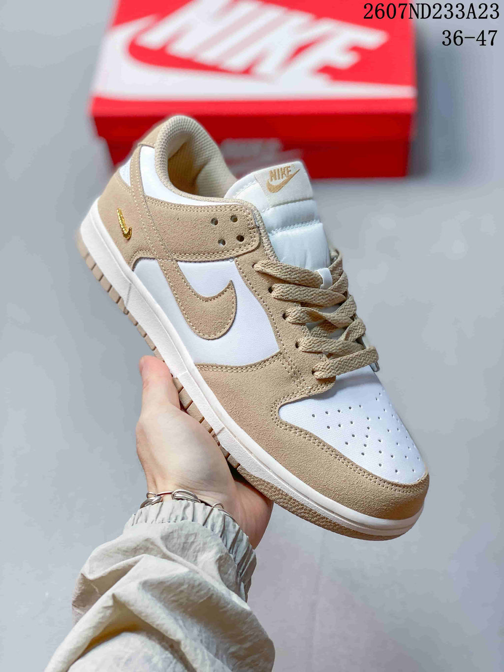 Close-up side view of a white and tan low-top sneaker showing the swoosh, perforated toe box, laces, and padded tongue.