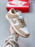Close-up side view of a white and tan low-top sneaker showing the swoosh, perforated toe box, laces, and padded tongue.