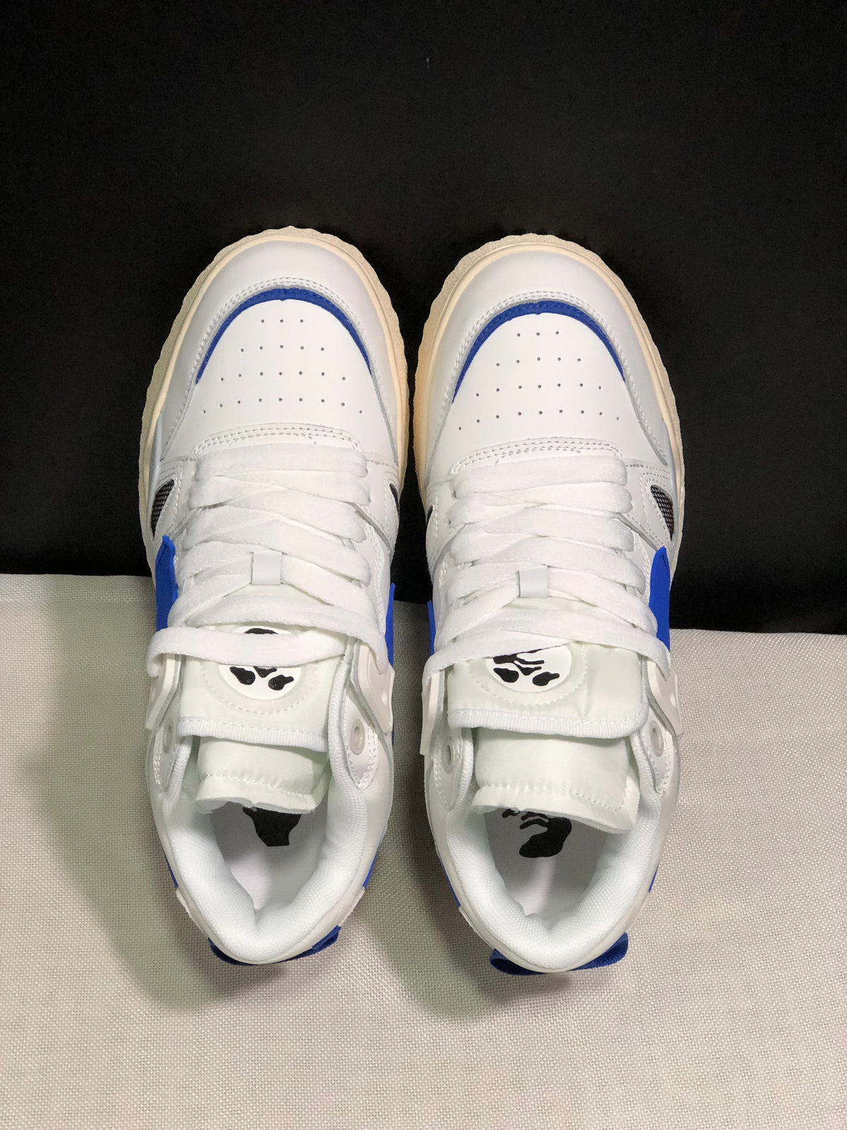 Top view showing the white perforated toe boxes, royal blue trim, white laces, and tongue graphics.