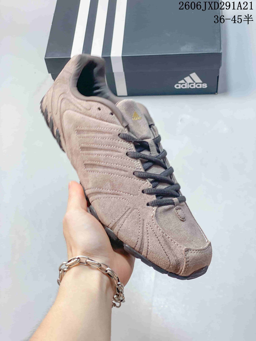 Angled side view showing the beige-taupe upper, layered detailing and black outsole.