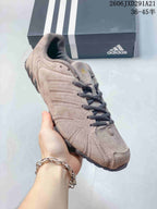 Angled side view showing the beige-taupe upper, layered detailing and black outsole.