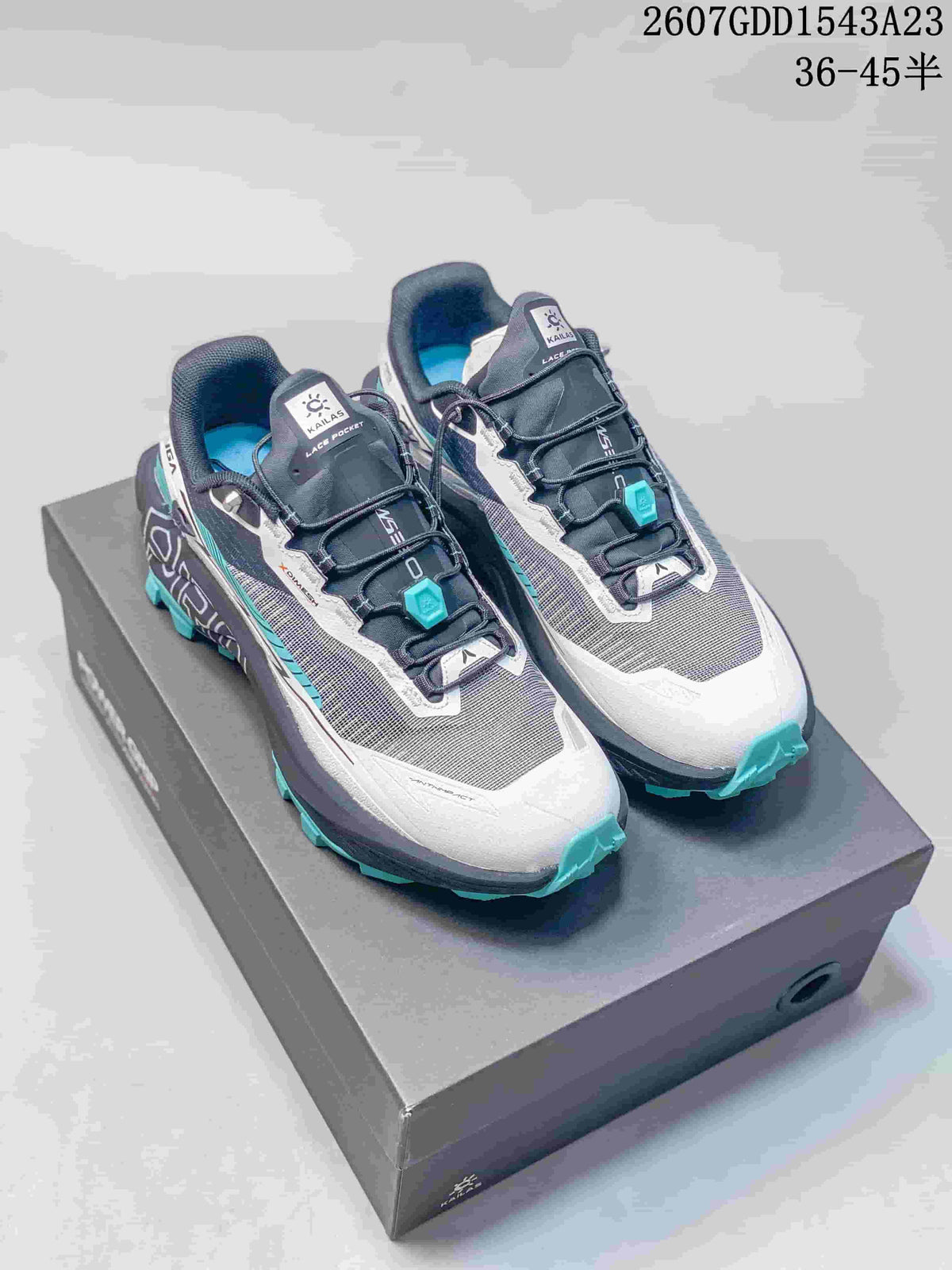 Pair of Kailas FUGA EX PRO trail running shoes in gray, white and teal displayed on a shoebox; style code and size range are overlaid above.