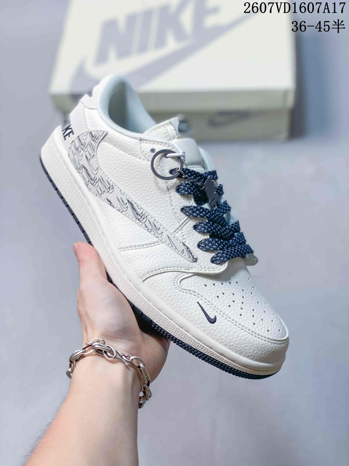 White low-top sneaker with monochrome graphic side panel, dark laces, metal lace accessories and a pale branded box behind it.