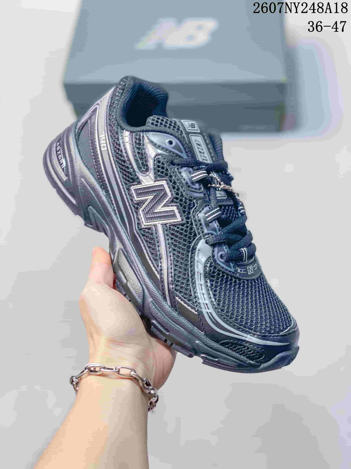 Angled side view of a black and gray New Balance 740-style sneaker showing the mesh upper, layered overlays, side logo, and cushioned-looking sole.