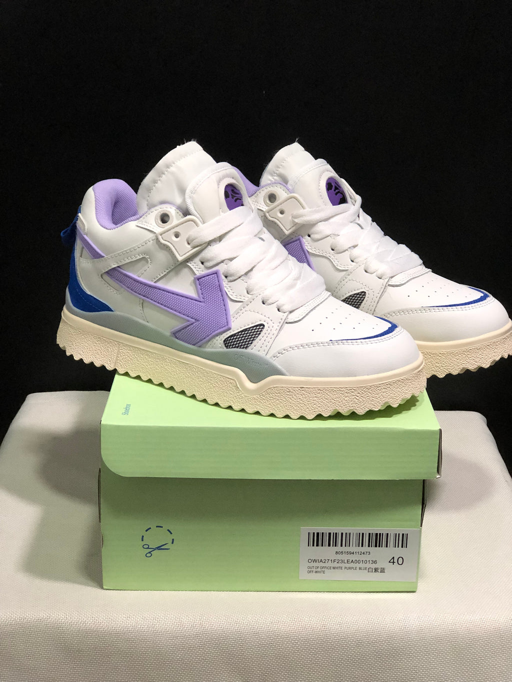 Pair of white Off-White sneakers with purple and blue accents displayed on a green shoe box; the box label shows size 40.