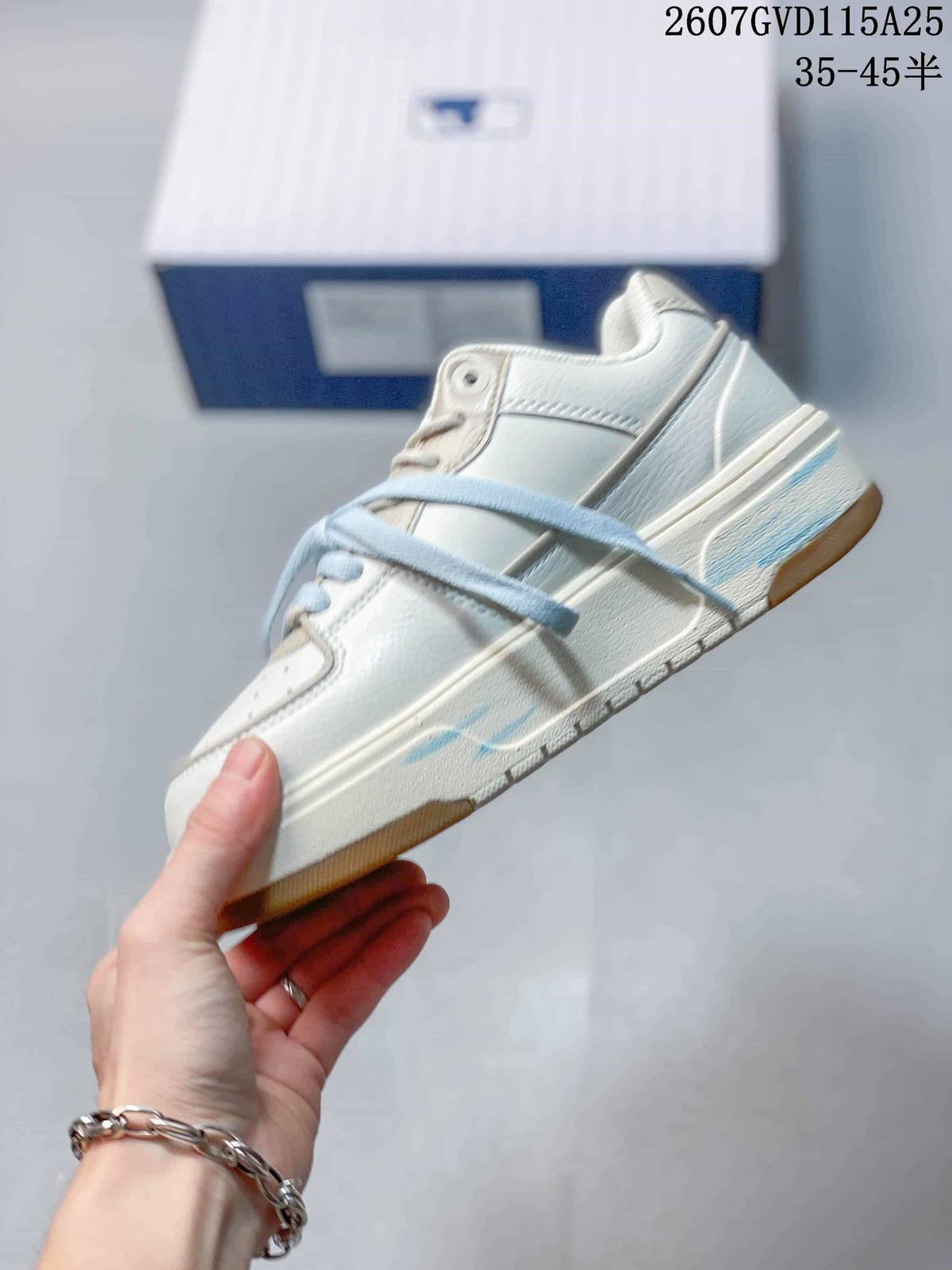 Side profile of the low-top sneaker showing layered panels, pale blue accents, and a gum-colored outsole edge.