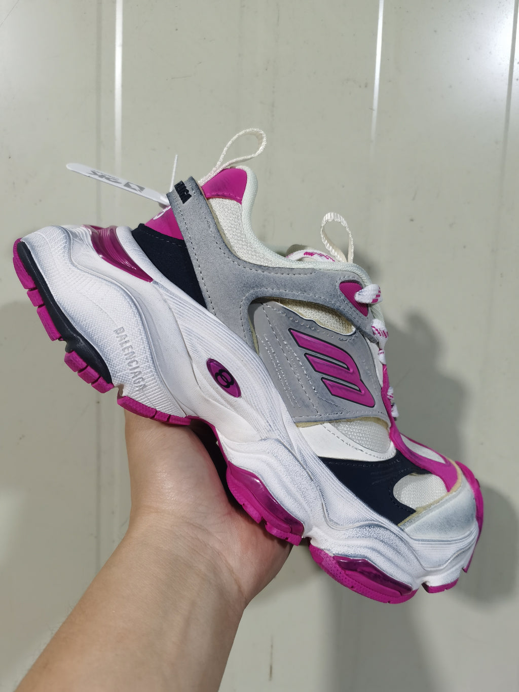Angled close-up of the sneaker showing the Balenciaga branding, pink outsole details, layered upper and rear pull tab.