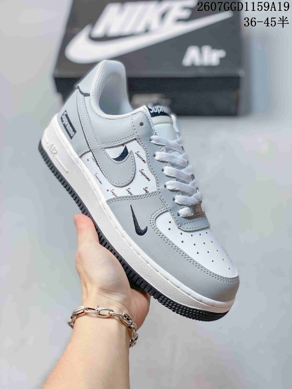 White and light gray low-top sneaker with repeated script-style graphics, white laces, and a dark outsole; style code 2607GGD1159A19 and size range 36-45 are overlaid.