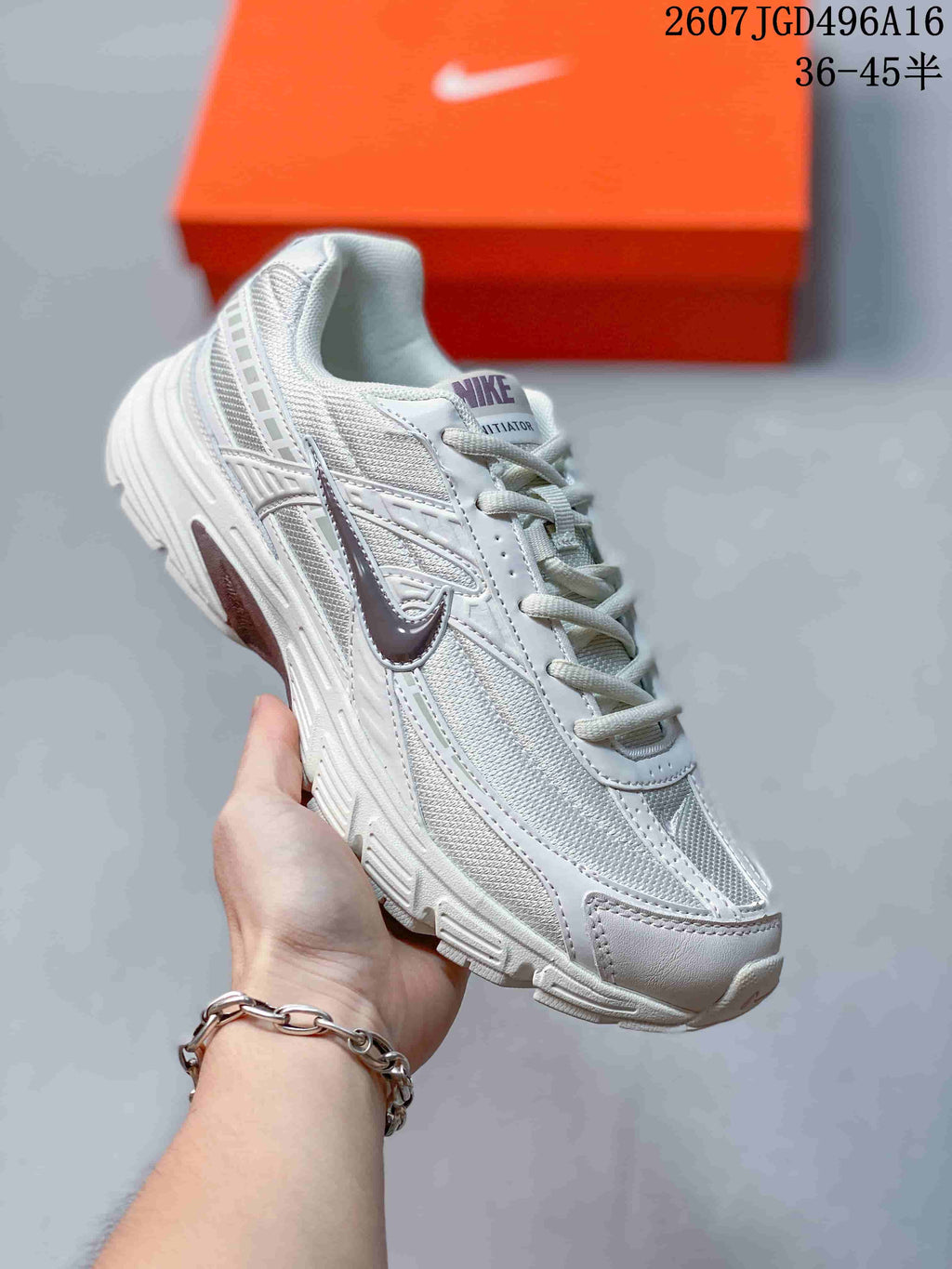 Angled side view of a white and grey Nike Initiator sneaker showing the layered retro running-shoe construction and chunky sole.