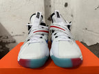 Front view of white Nike sneakers with printed midfoot straps and translucent red-and-blue outsoles.
