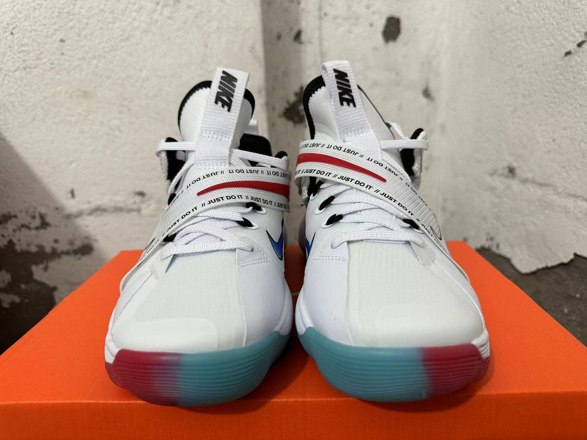 Front view of white Nike sneakers with printed midfoot straps and translucent red-and-blue outsoles.