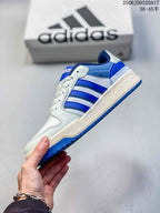 Side view of the adidas Entrap sneaker showing the blue three-stripe detail, white upper panels and blue outsole.