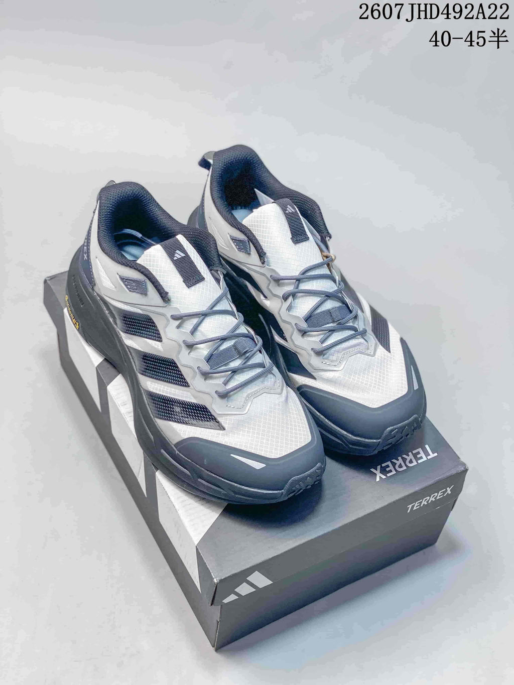Pair of white, black and gray Adidas Terrex hiking shoes displayed on a Terrex shoe box.