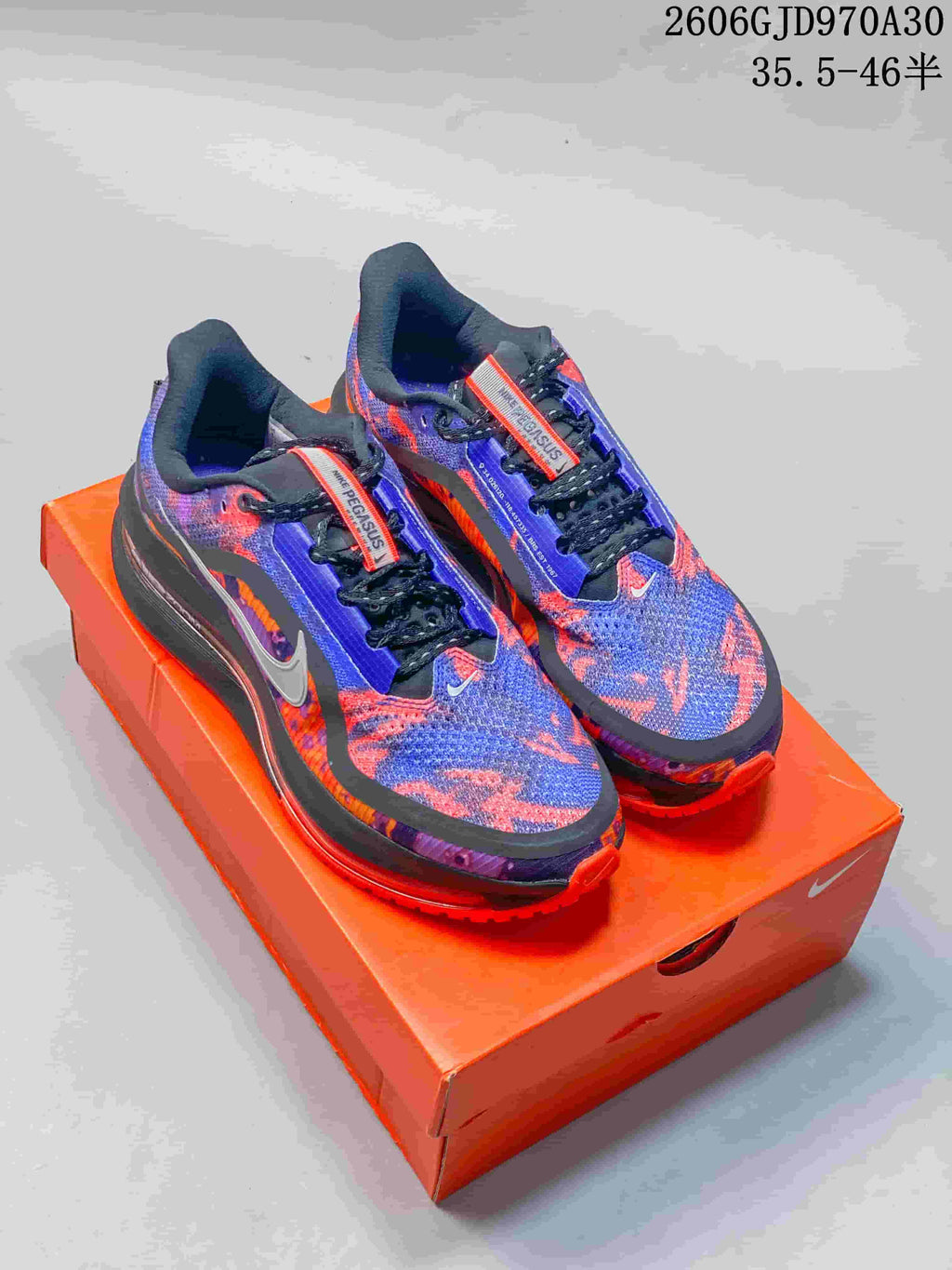 Pair of blue, purple, and orange Nike Air Zoom Pegasus Premium running shoes on an orange shoe box