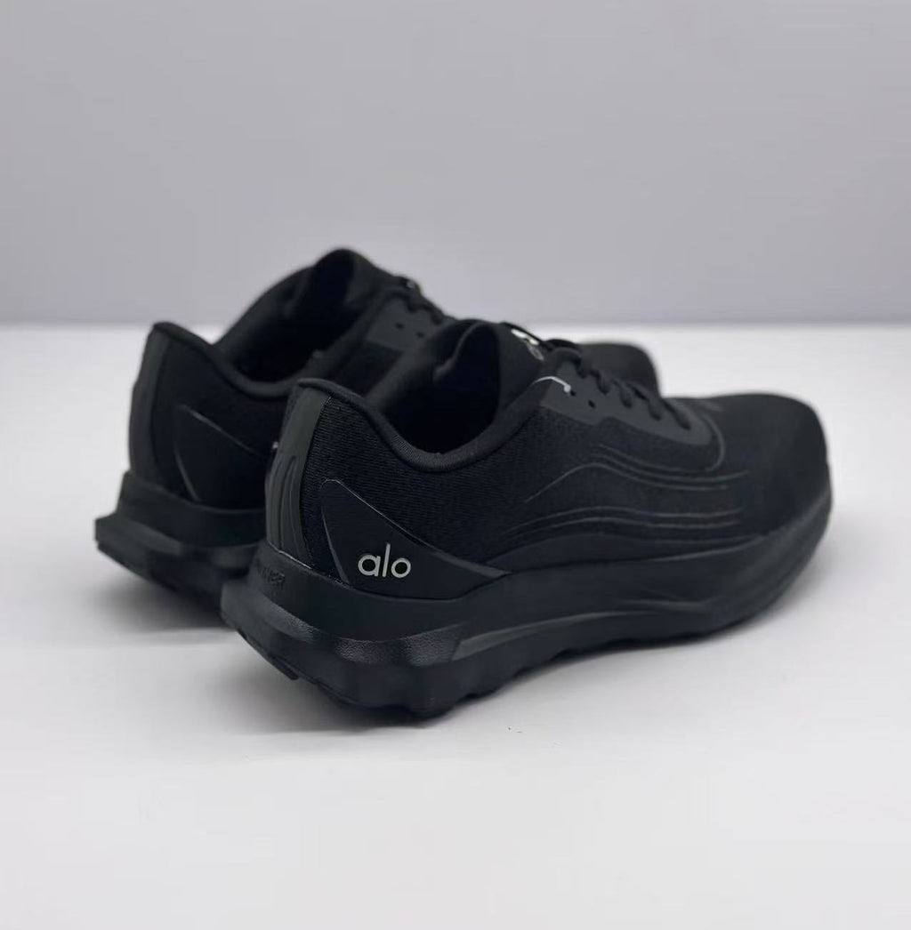 Rear three-quarter view of the black Alo sneakers showing the heel branding, padded collars, and raised outsole.