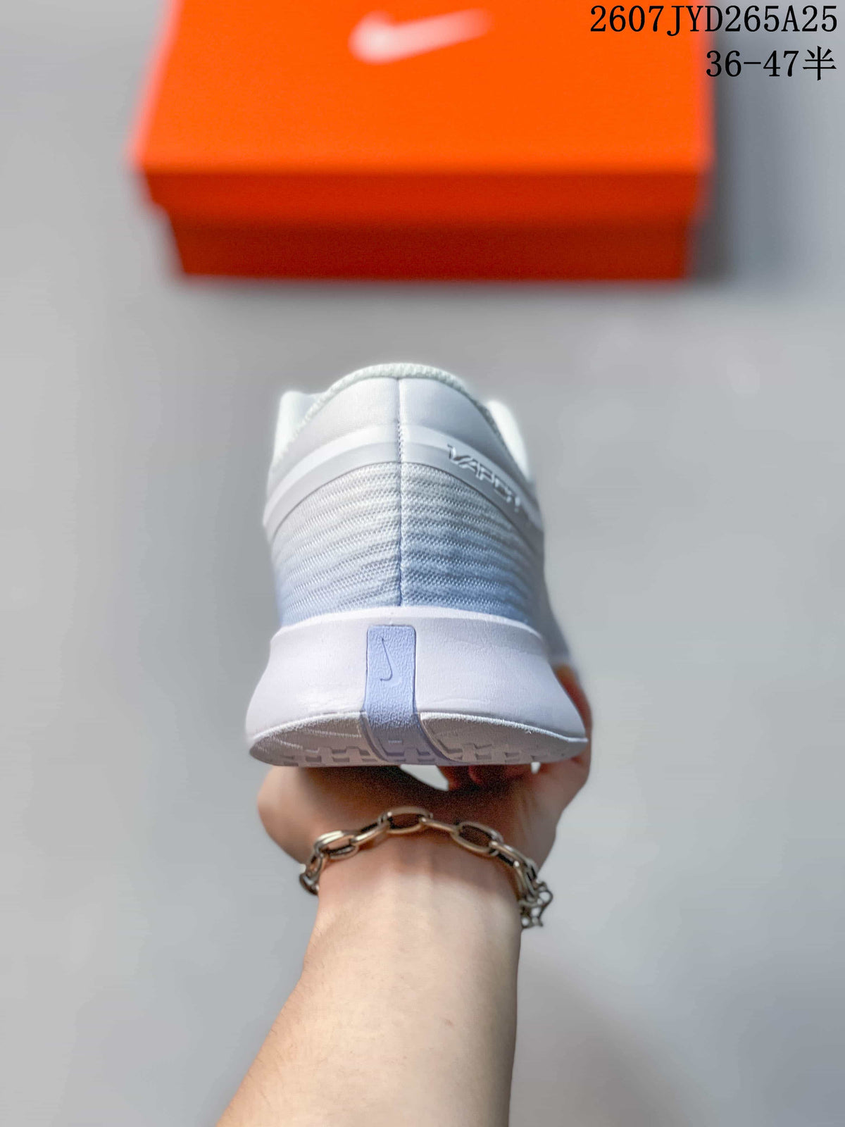Rear view showing the padded collar, heel structure and outsole pattern of the white tennis shoe.