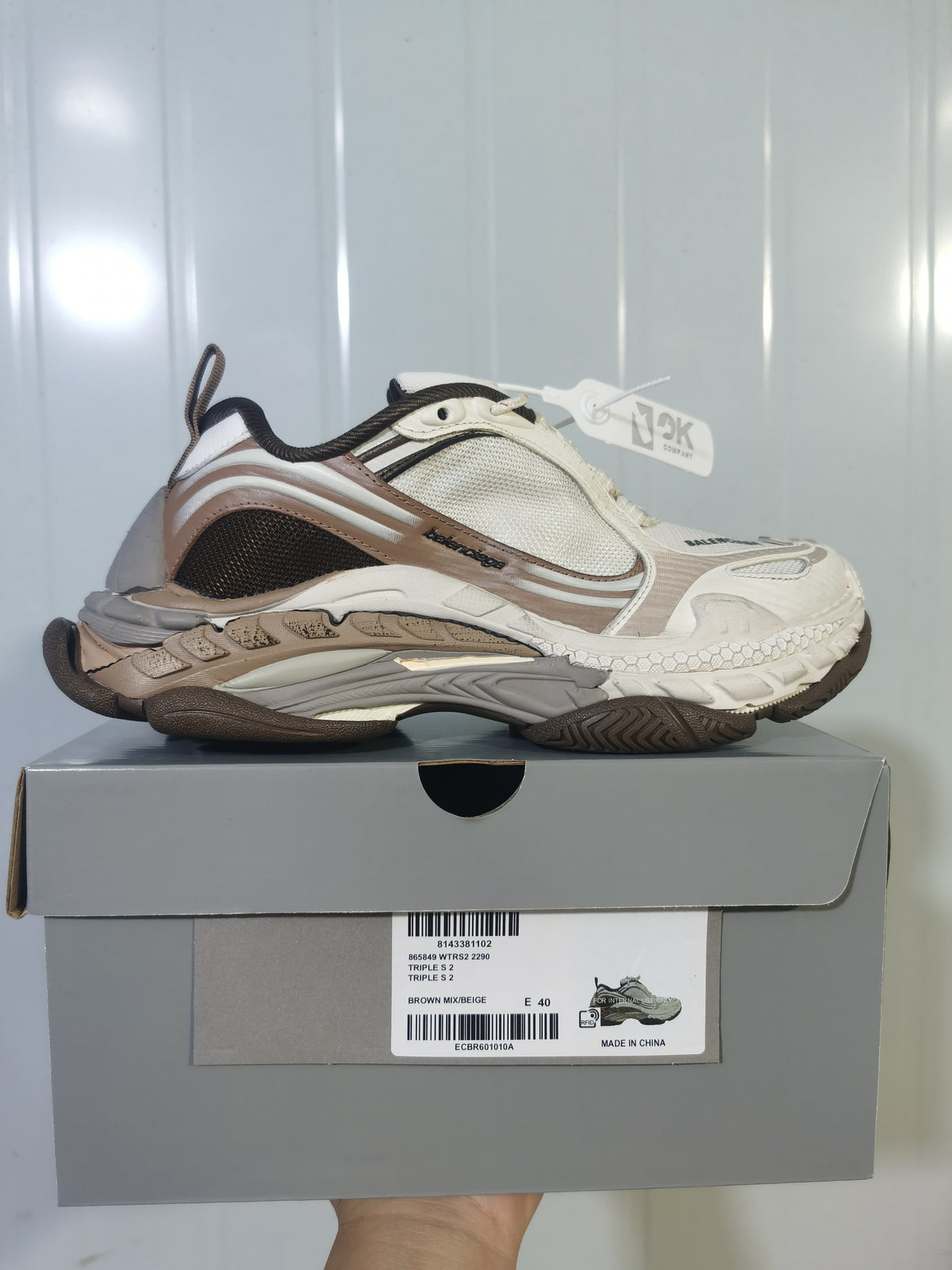Side view of Balenciaga Triple S 2 2290 sneakers in brown, beige, white, and grey, displayed on the labeled shoe box.