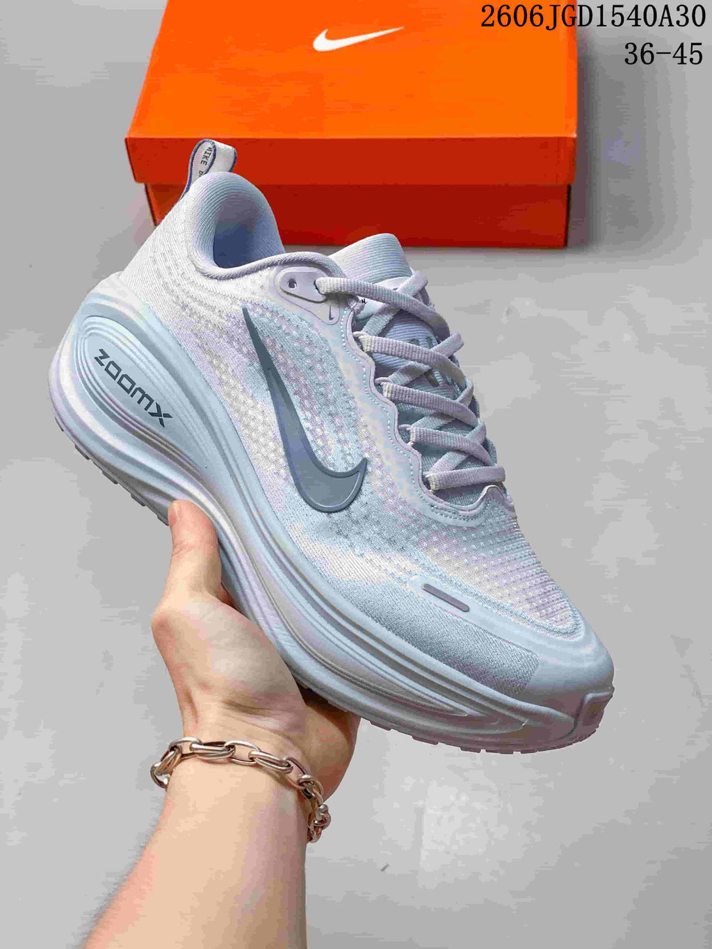 Pale blue and white Nike Vomero Plus running shoe with a gray Swoosh.
