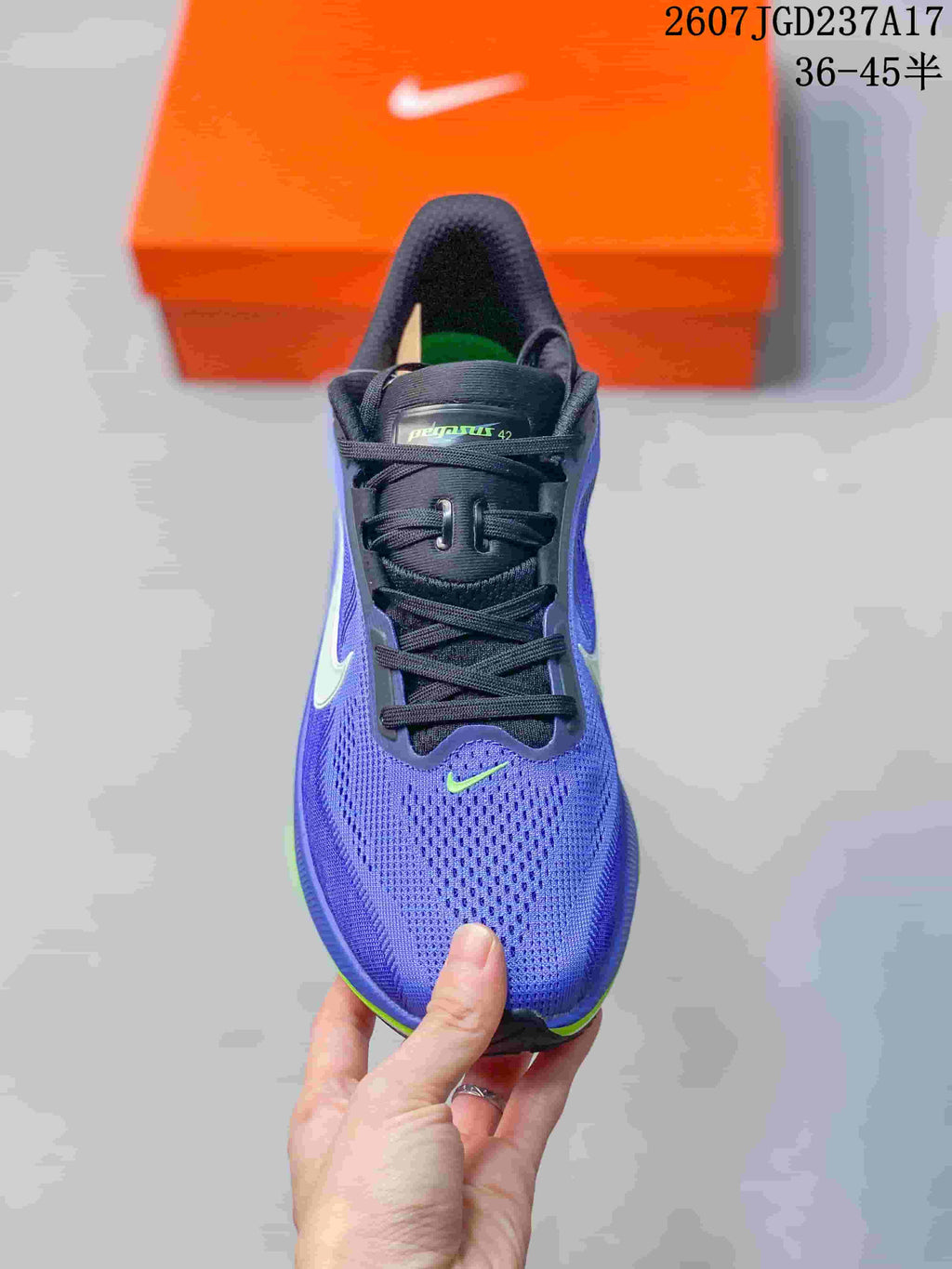 Top view of a purple and blue Nike Air Zoom Pegasus 42 shoe showing the perforated toe area, black laces, and small bright green Swoosh.