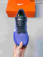 Top view of a purple and blue Nike Air Zoom Pegasus 42 shoe showing the perforated toe area, black laces, and small bright green Swoosh.