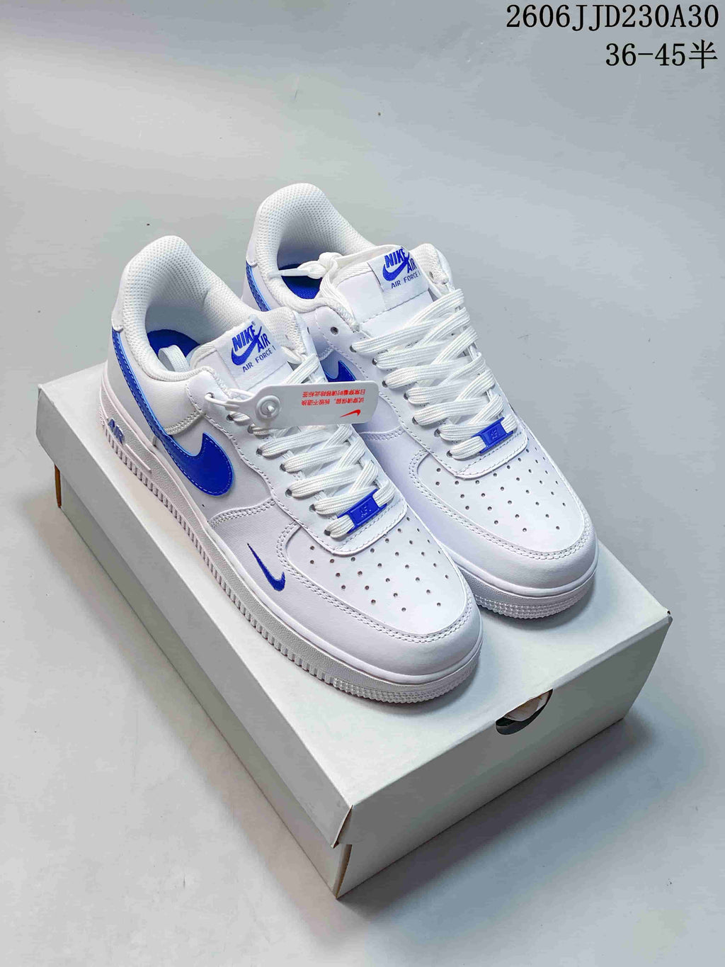 Pair of white low-top sneakers with blue accents on a shoe box