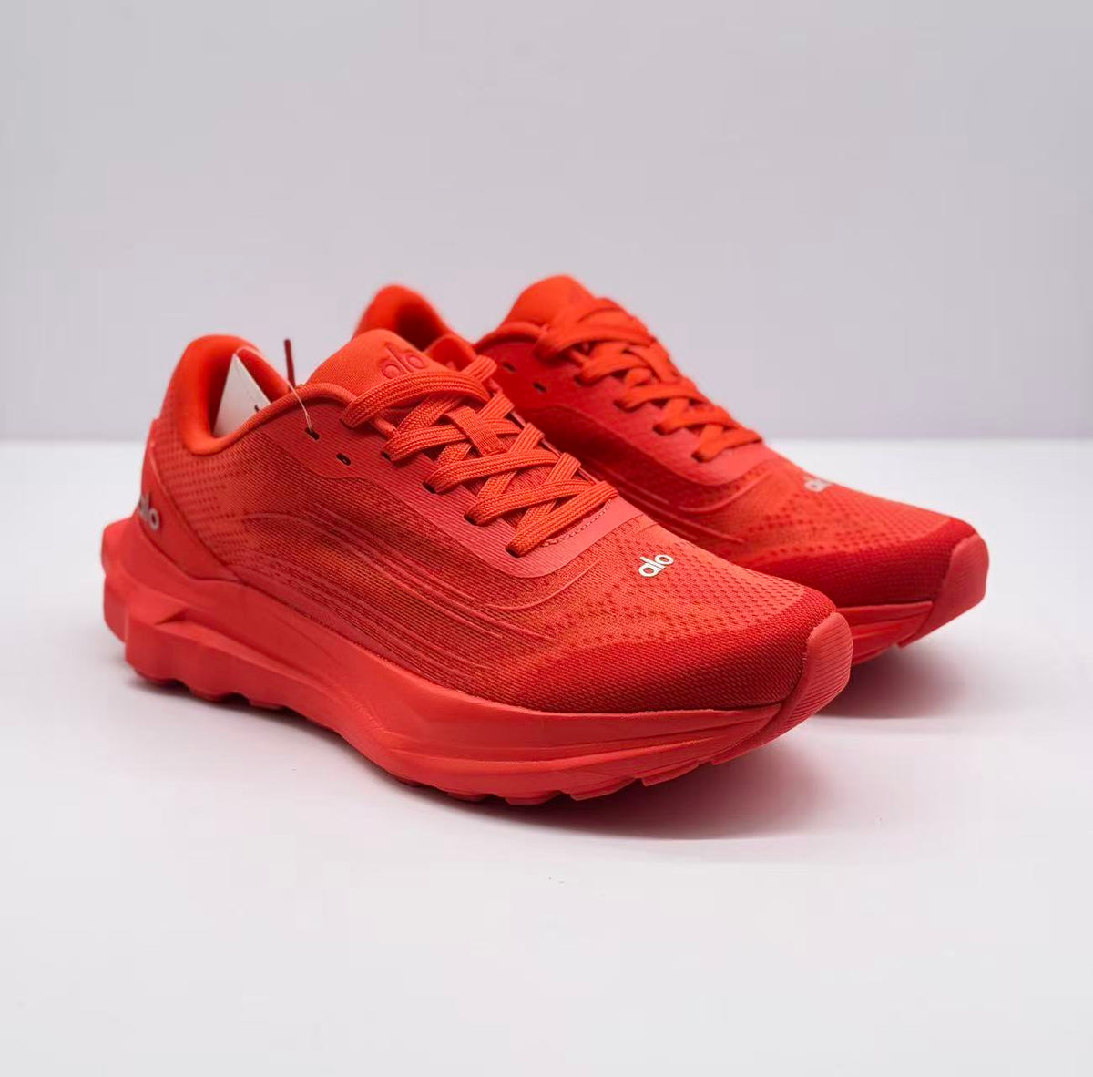 Pair of red alo sneakers shown from a three-quarter front angle.