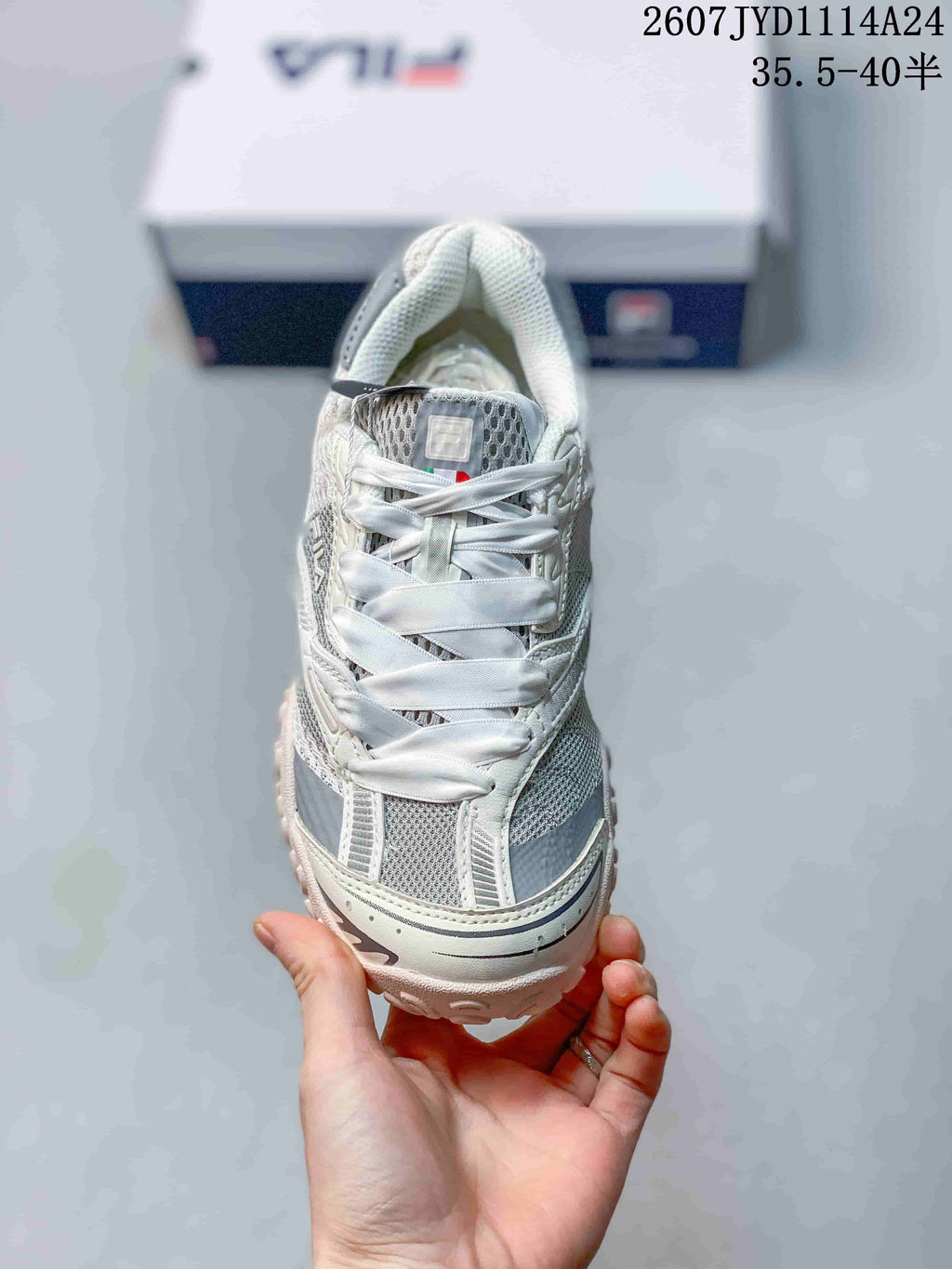 Front view of the sneaker showing wide flat laces, mesh-style panels, and the layered toe area.