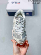 Front view of the sneaker showing wide flat laces, mesh-style panels, and the layered toe area.