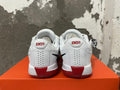 Rear view of white Nike basketball shoes with red heel accents and dark outsole details.