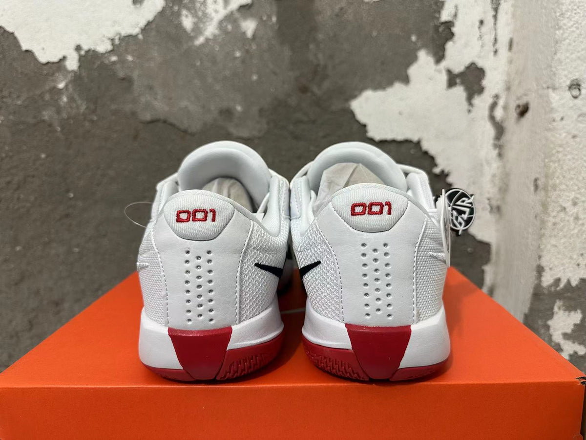 Rear view of white Nike basketball shoes with red heel accents and dark outsole details.