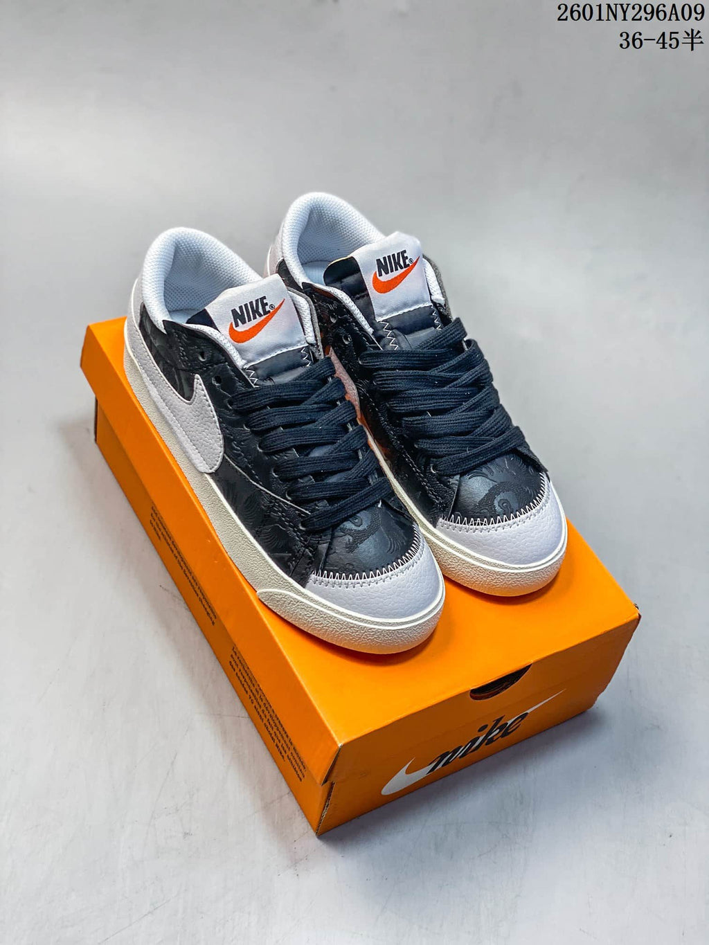 Pair of black and white Nike Blazer Low '77 Jumbo sneakers displayed on an orange shoebox.