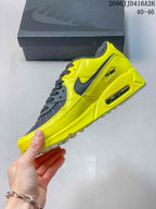 Side view of the yellow and black Nike Air Max 90 sneaker showing the layered panels, side Swoosh, and heel window.