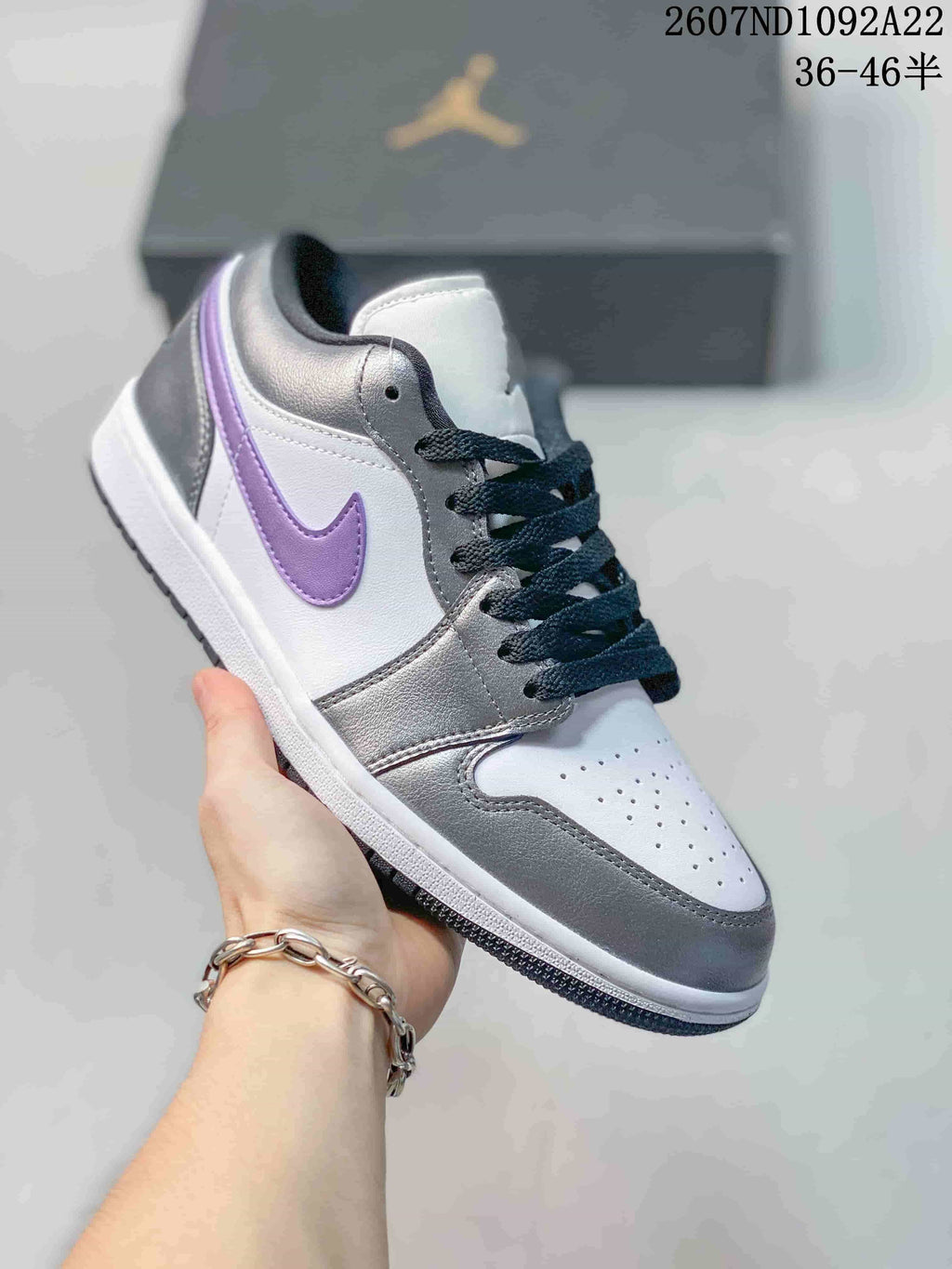 White and gray low-top Jordan sneaker with a purple Swoosh and black laces.
