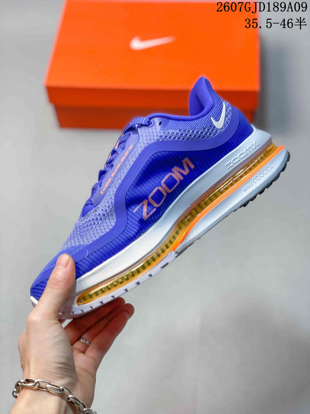 Side profile of the blue Nike Vomero shoe showing the VOMERO lettering, layered side panels and visible orange cushioning unit.