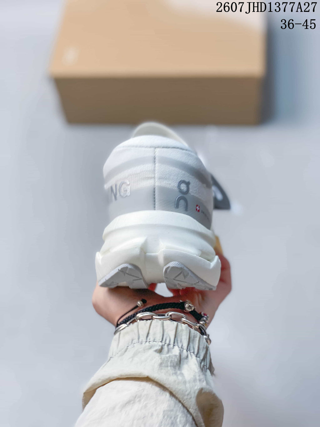 Rear view of a white On sneaker showing the padded heel, white outsole sections, and yellow midsole accent.