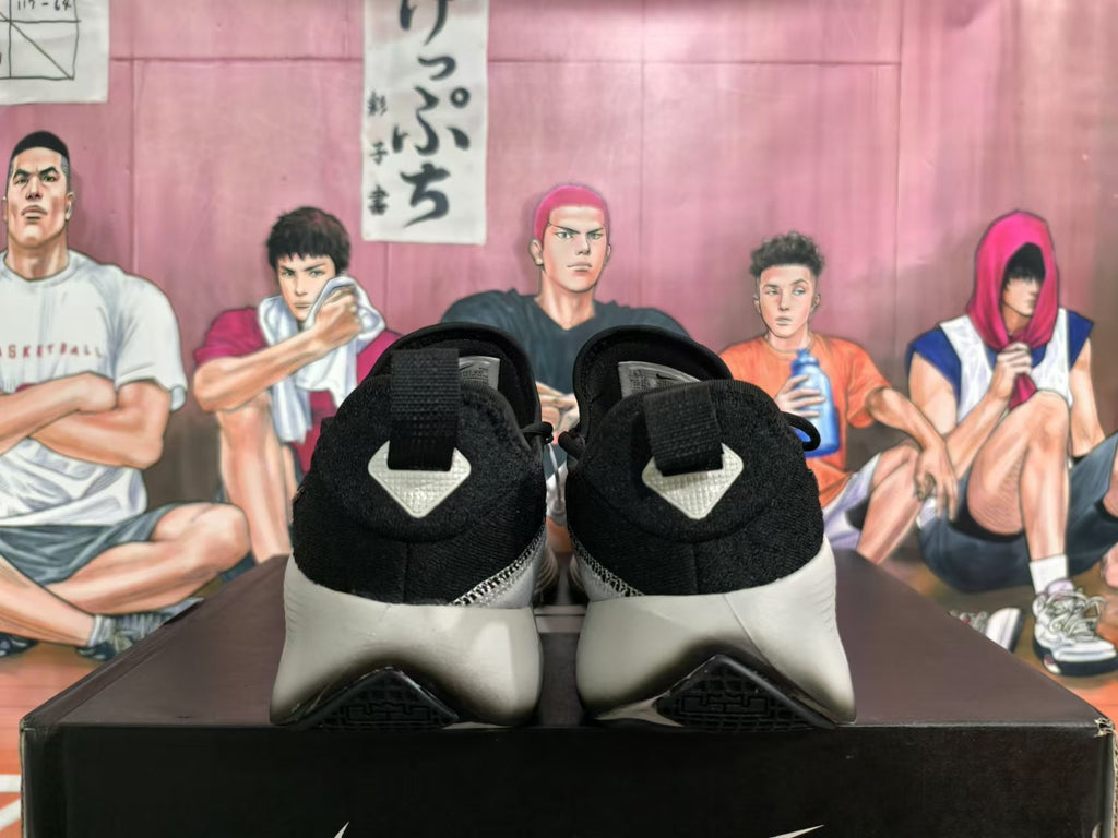 Rear view of black Nike sneakers with pale gray sculpted heels and a basketball-themed display behind them.