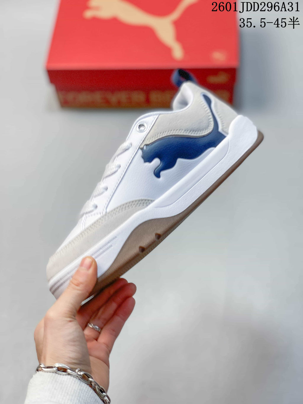 Side view showing the white upper, blue PUMA side logo, gray detailing, and raised sole.