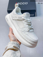 Angled view of the white sneaker showing its mesh panels and thick platform-style sole.