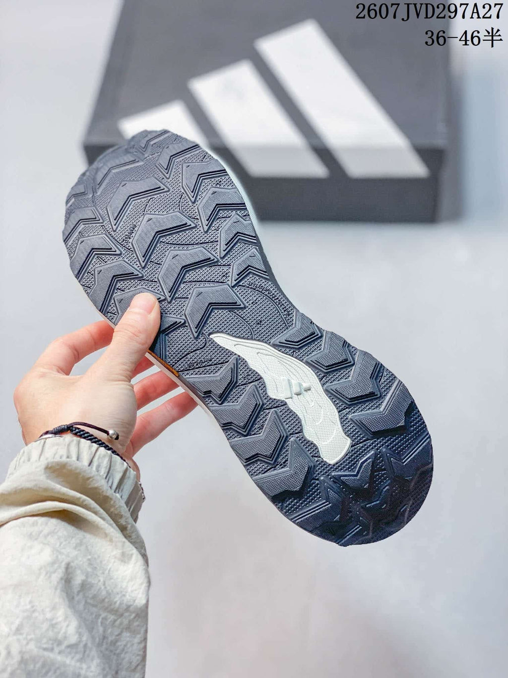 Close view of the dark patterned outsole showing directional tread across the shoe bottom.