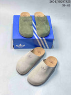 Green and light beige Adimule slides shown together from above, with Adidas branding visible on the uppers and footbeds.