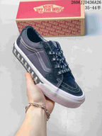 Angled side view showing the black Vans SK8-Low sneaker, white side stripe, skull graphics, and white rubber sole.